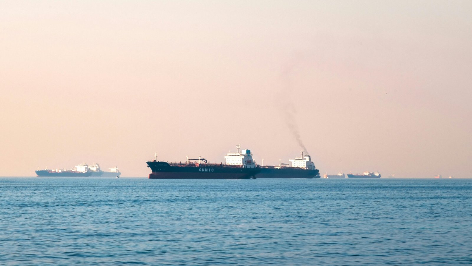 Large industrial tanker ships navigating the open sea under a clear sky, illustrating maritime transportation.